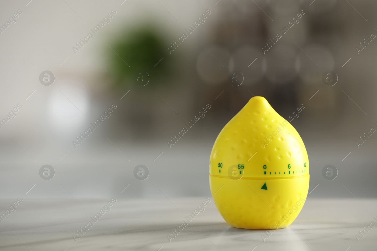 Photo of Kitchen timer in shape of lemon on white table against blurred background. Space for text