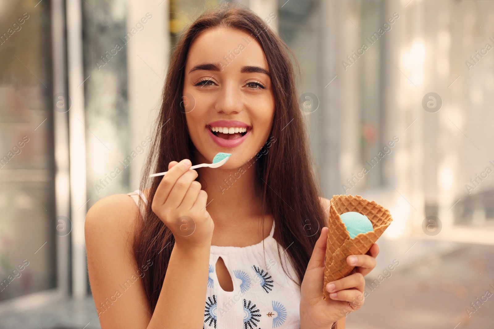 Photo of Happy young woman with delicious ice cream in waffle cone outdoors