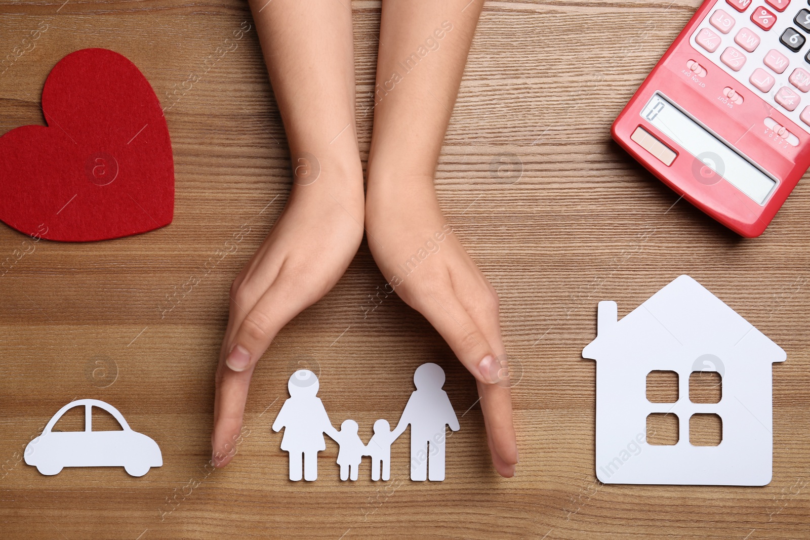 Photo of Woman holding hands over paper silhouette of family on wooden background, top view. Life insurance concept