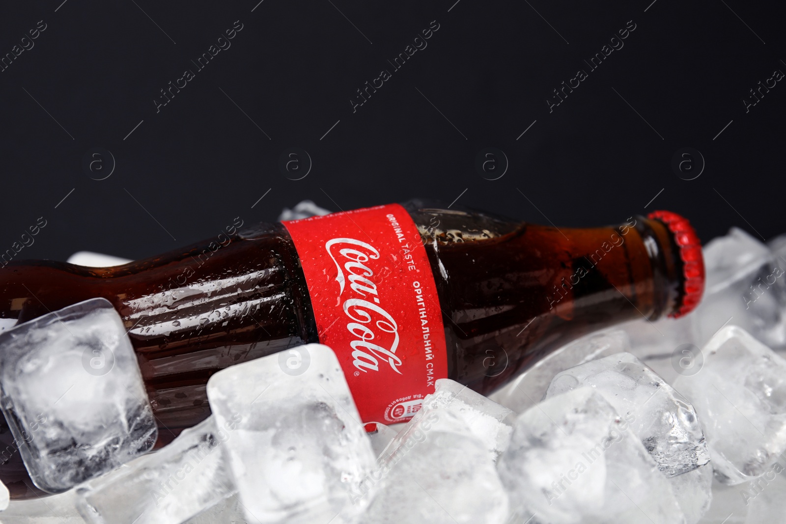 Photo of MYKOLAIV, UKRAINE - NOVEMBER 15, 2018: Bottle of Coca Cola on ice cubes against black background