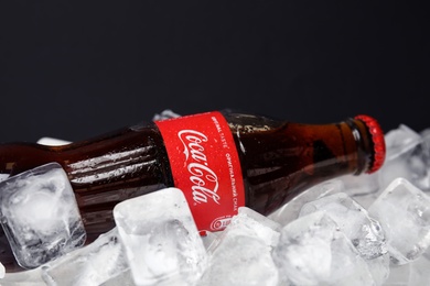 Photo of MYKOLAIV, UKRAINE - NOVEMBER 15, 2018: Bottle of Coca Cola on ice cubes against black background