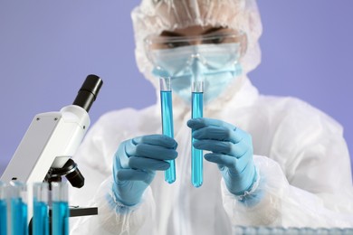Scientist working with test tubes of light blue liquid on grey background, closeup