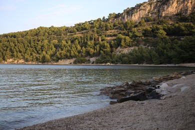 Picturesque view of green trees and rocks near tranquil sea