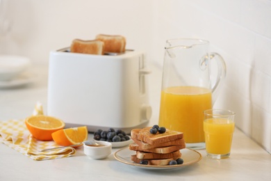 Photo of Modern toaster and tasty breakfast on white table in kitchen