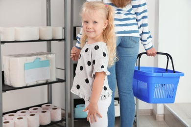 Young mother and little girl choosing toilet paper in shop