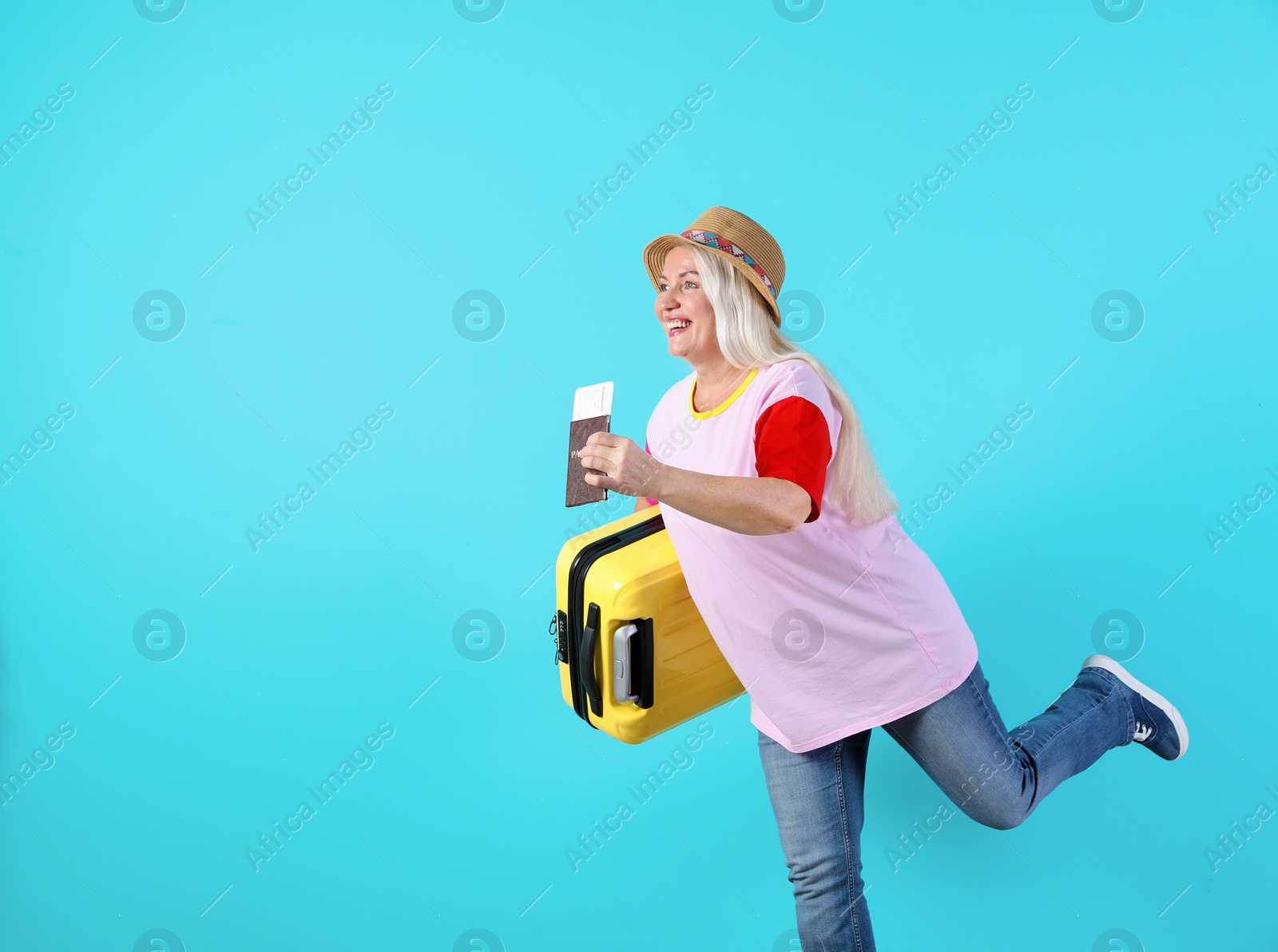 Photo of Senior woman with suitcase and passport running on color background. Space for text