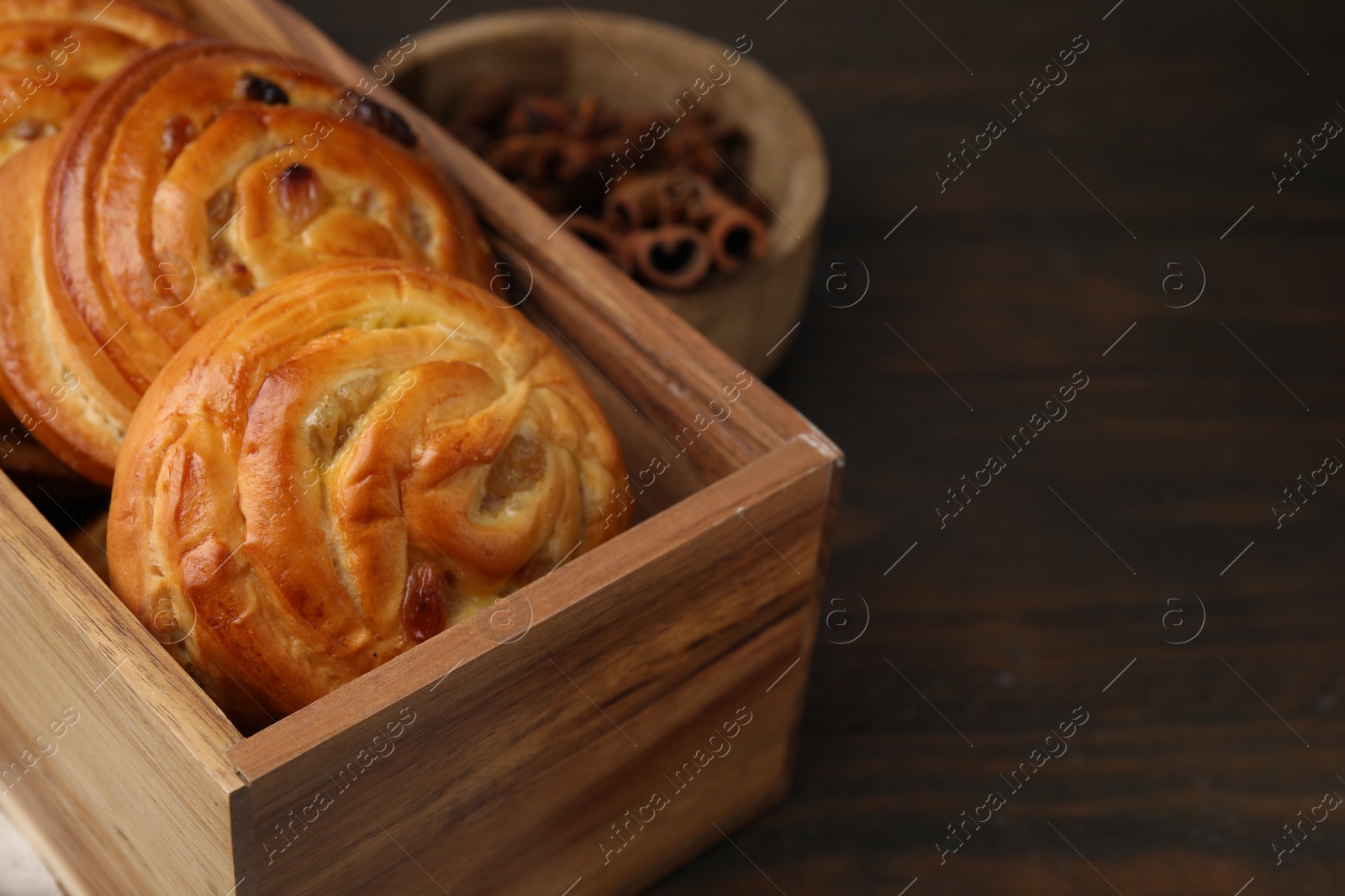 Photo of Delicious rolls with raisins on wooden table, closeup and space for text. Sweet buns