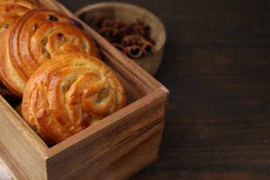 Delicious rolls with raisins on wooden table, closeup and space for text. Sweet buns