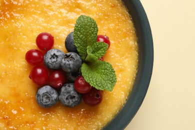 Photo of Delicious creme brulee with fresh berries on beige background, closeup