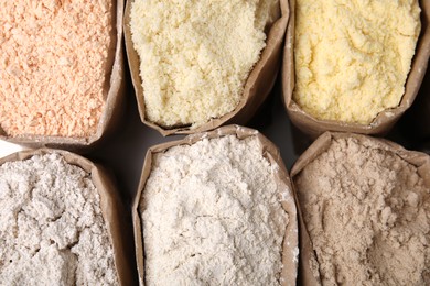 Photo of Paper sacks with different types of flour as background, closeup