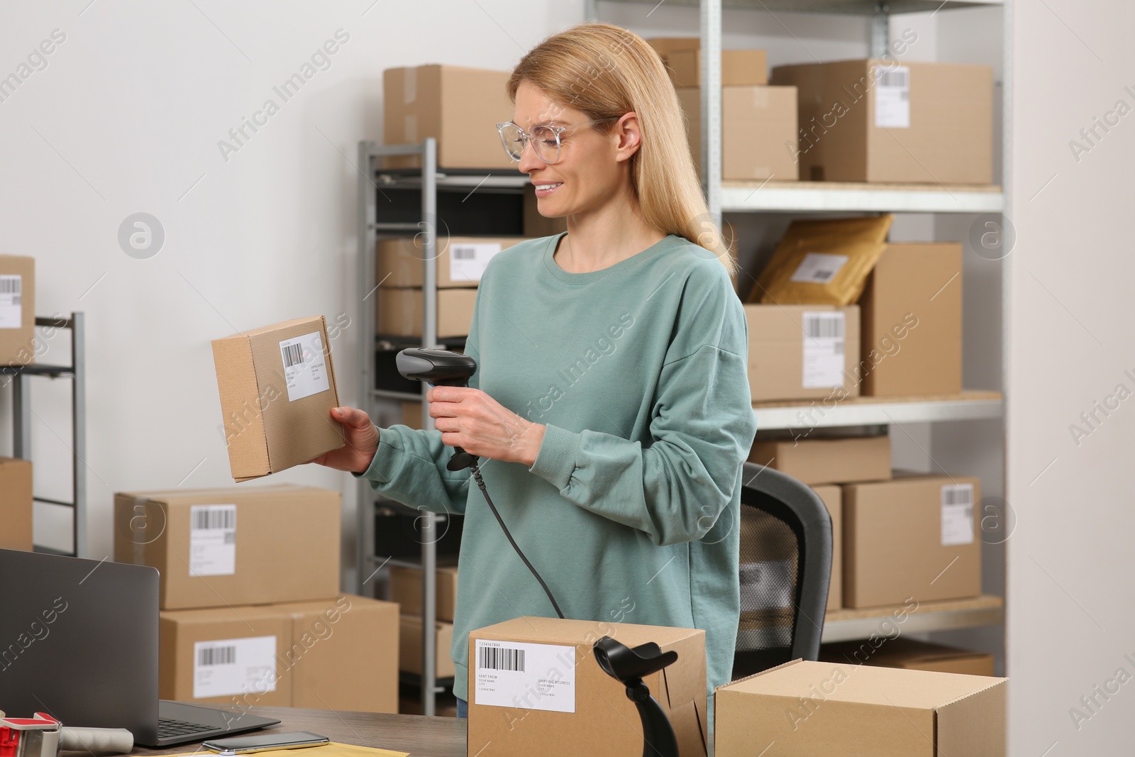 Photo of Seller with scanner reading parcel barcode in office. Online store