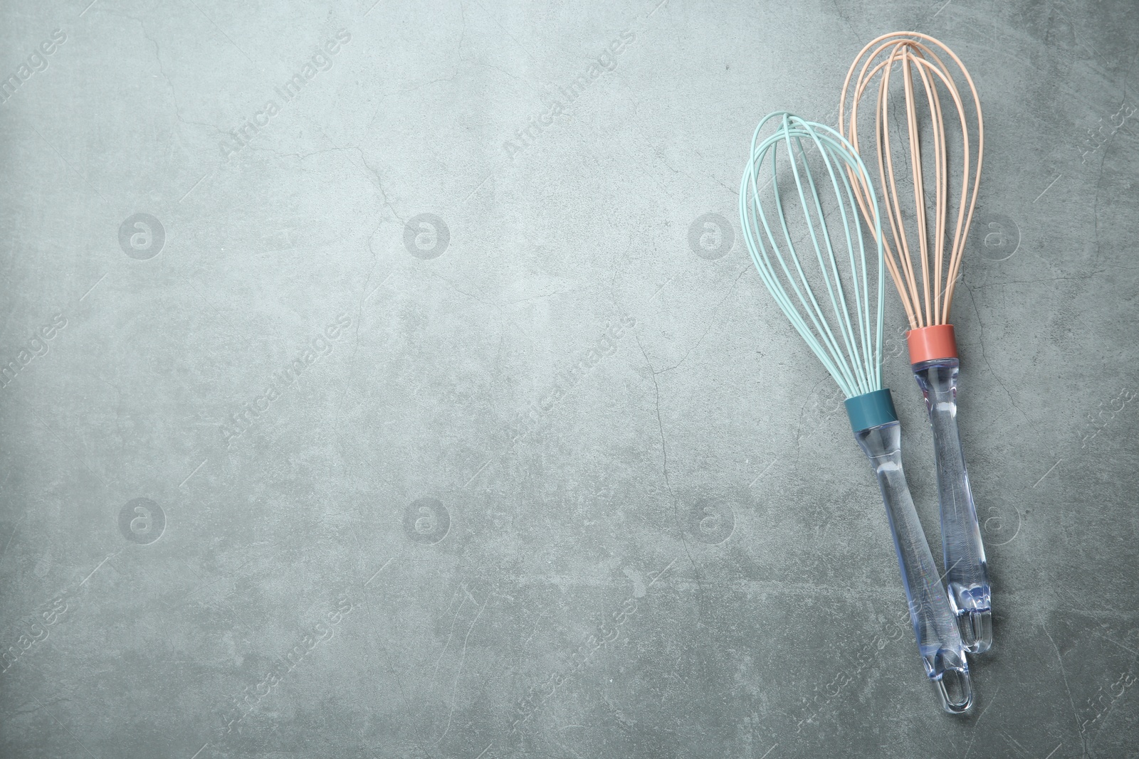 Photo of Two whisks on gray table, top view. Space for text
