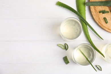 Photo of Flat lay composition with fresh aloe drink and leaves on white wooden table. Space for text