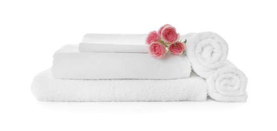 Photo of Fresh clean towels and bed sheets with roses on white background