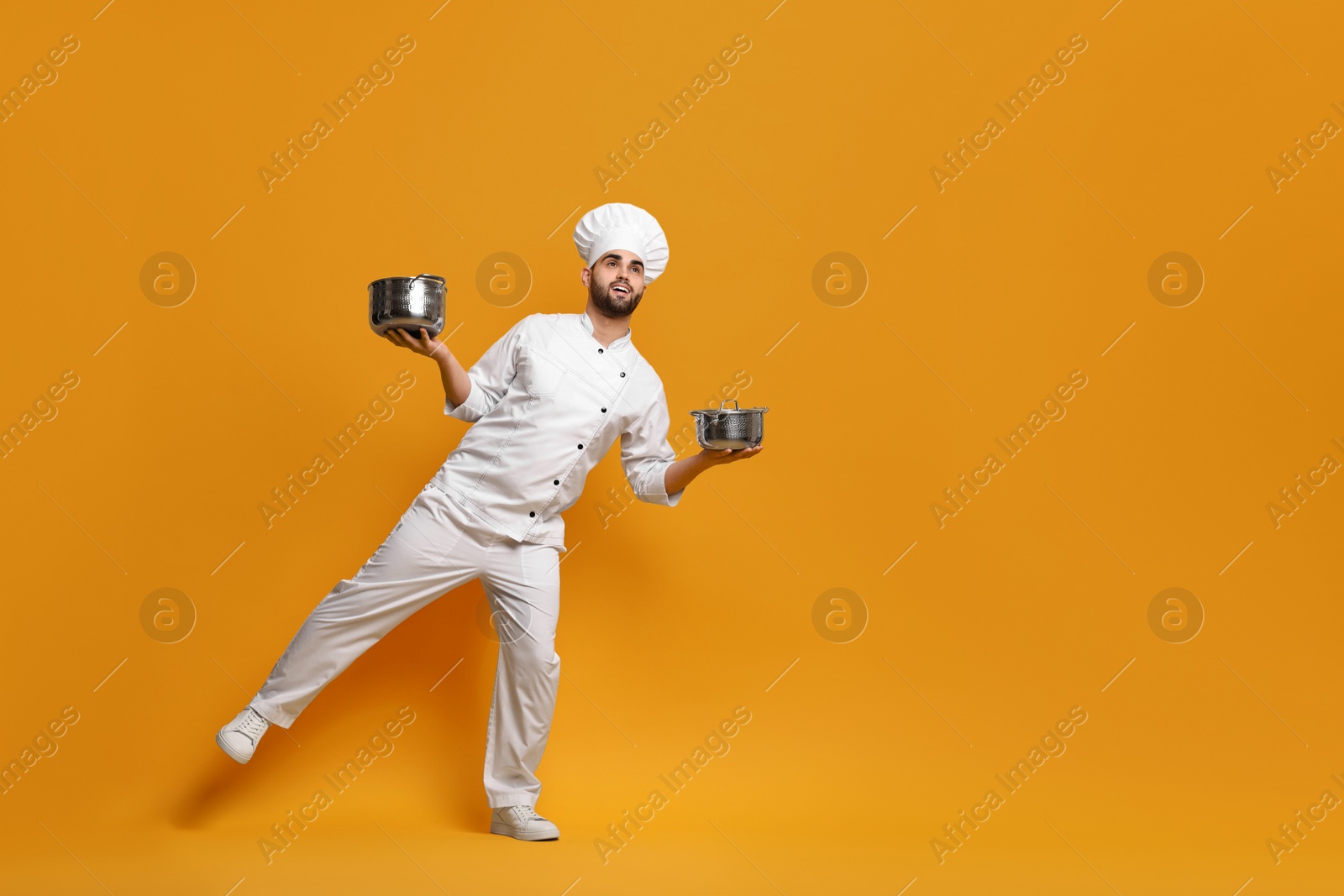 Photo of Professional chef with cooking pots on yellow background. Space for text