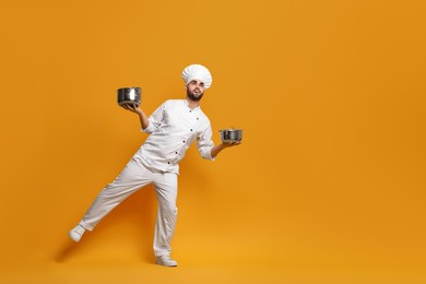 Photo of Professional chef with cooking pots on yellow background. Space for text