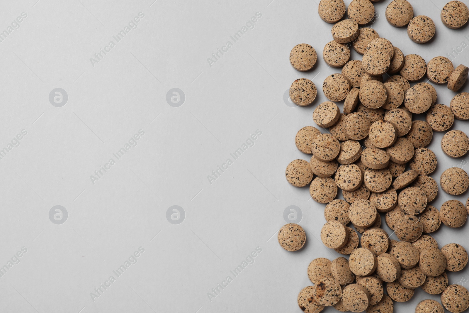 Photo of Vitamin pills on light grey background, top view. Space for text