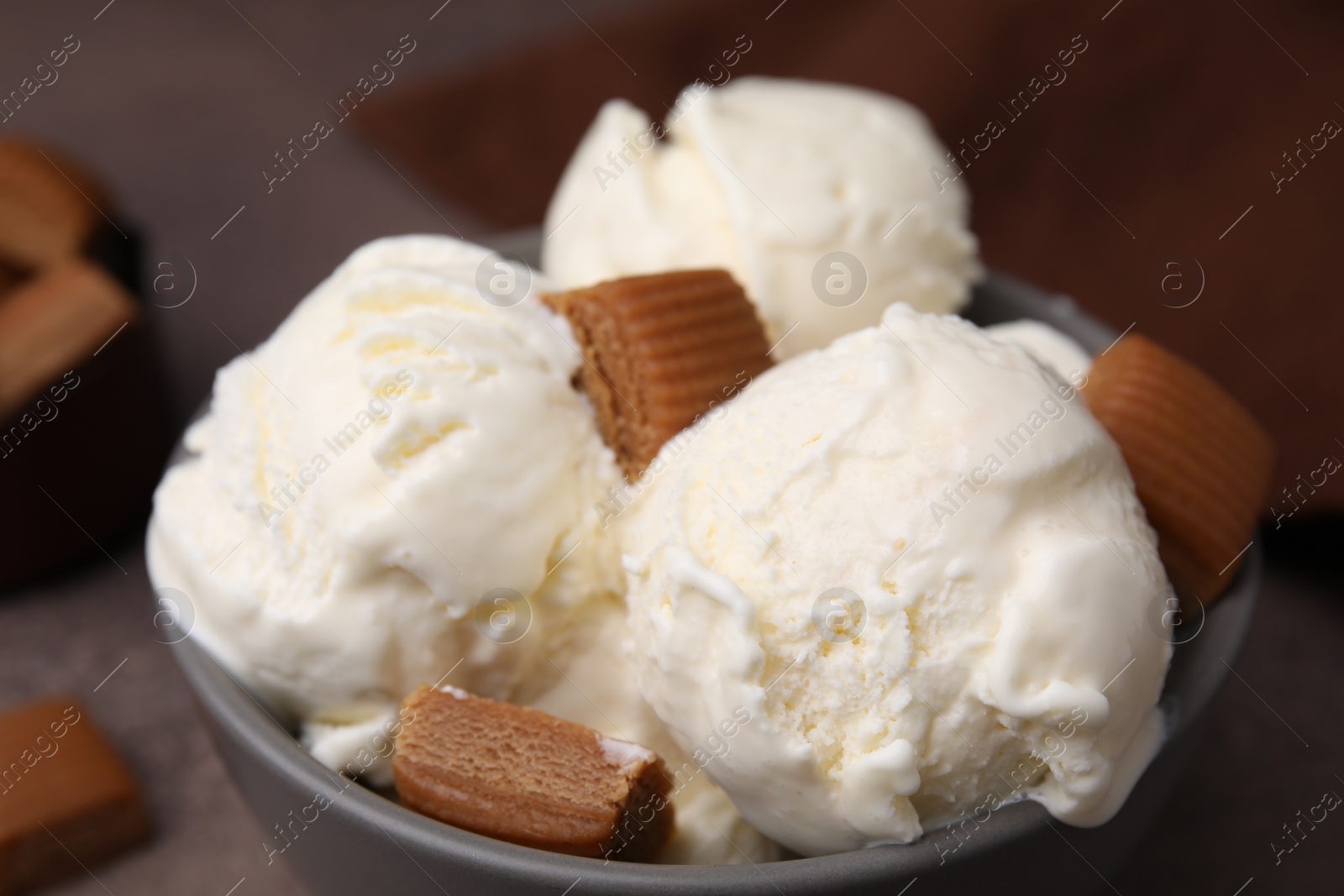 Photo of Scoops of ice cream with caramel candies in bowl on table, closeup
