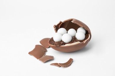 Broken chocolate egg with candies and filling isolated on white