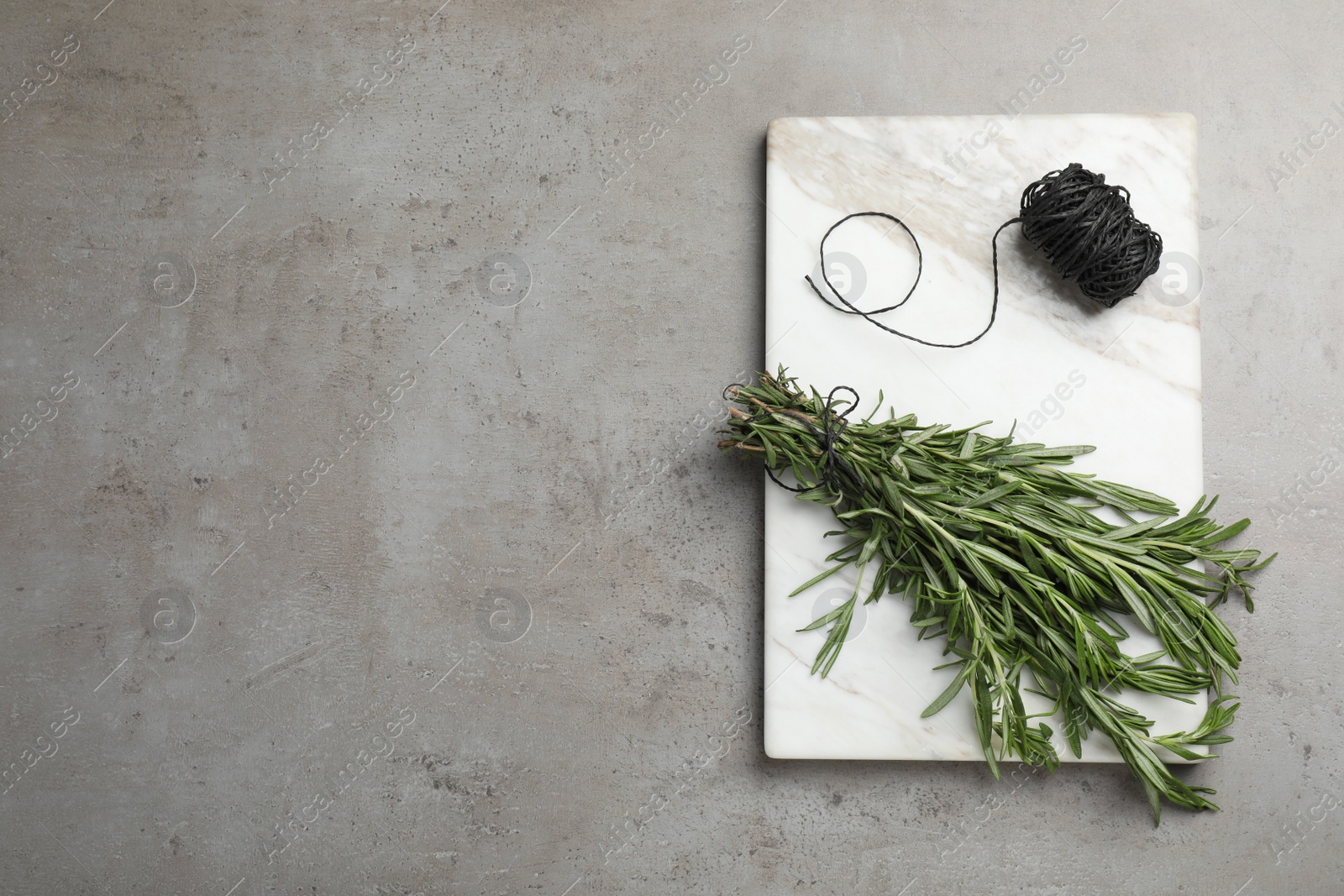 Photo of Bunch of fresh rosemary and twine on grey table, top view. Space for text