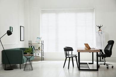 Photo of Modern medical office interior with doctor's workplace and sofa