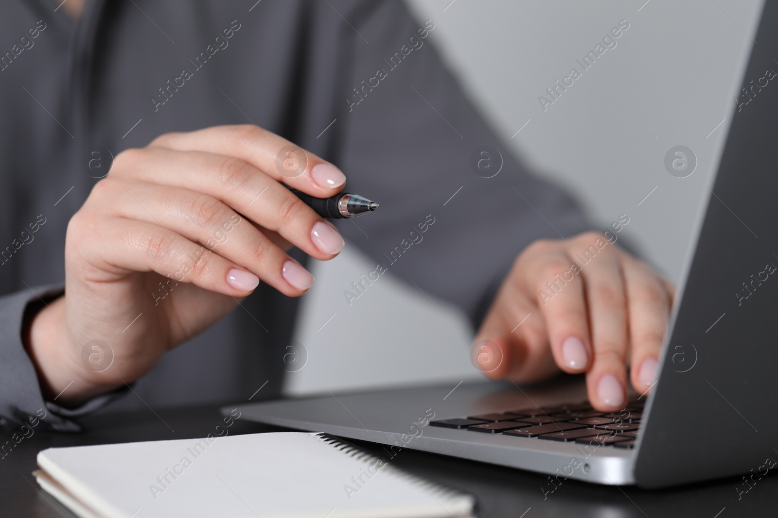 Photo of Woman with pen working on laptop, closeup. Electronic document management