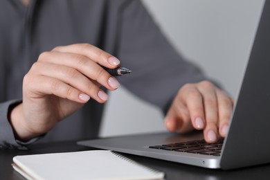 Woman with pen working on laptop, closeup. Electronic document management