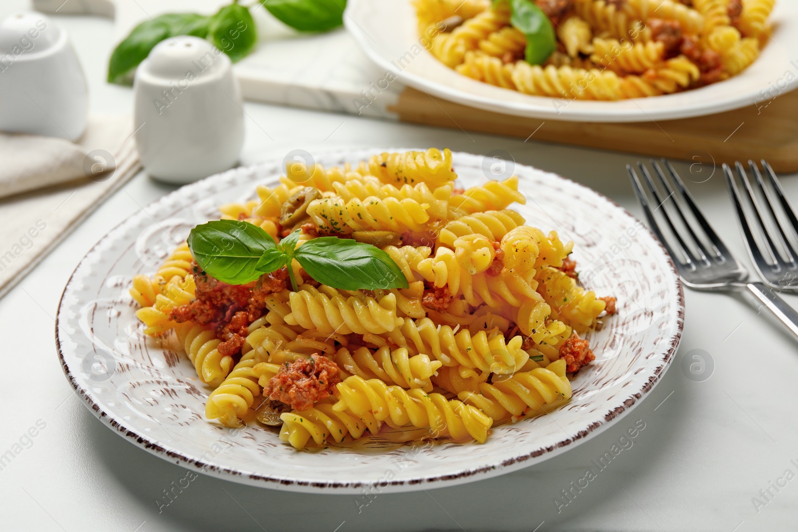 Photo of Delicious pasta with minced meat and basil served on white table, closeup