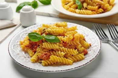 Delicious pasta with minced meat and basil served on white table, closeup