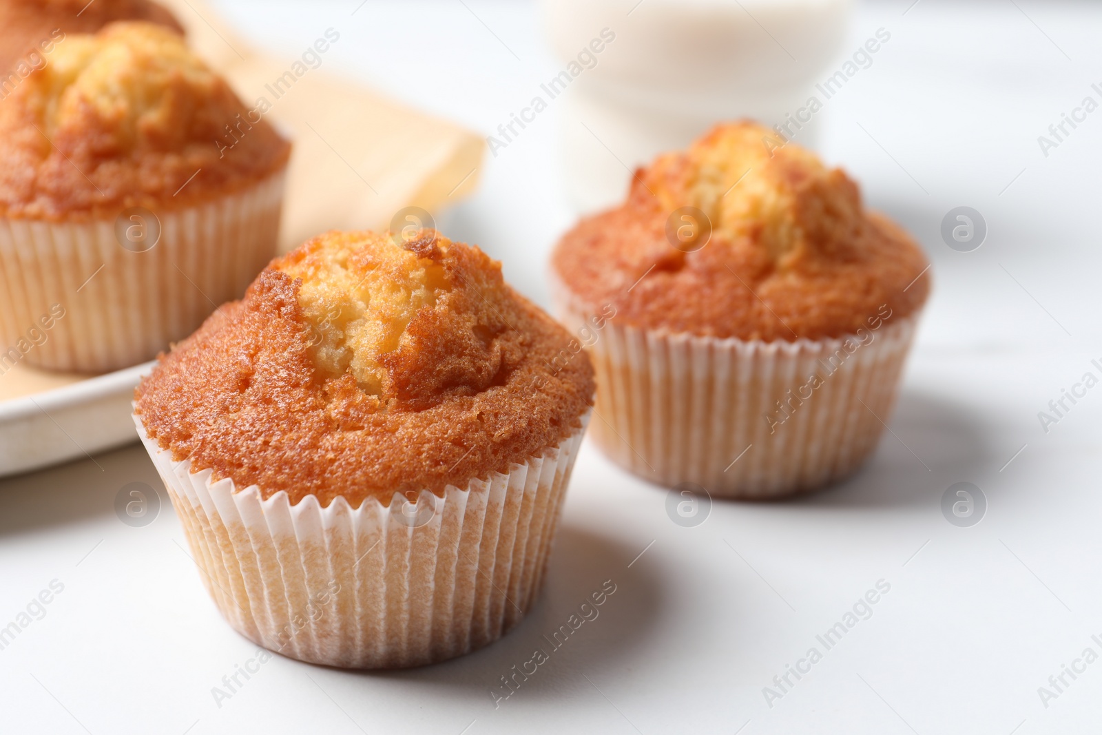 Photo of Delicious sweet muffins on white table, closeup. Space for text