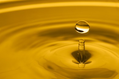 Image of Splash of golden oily liquid with drop as background, closeup. Space for text