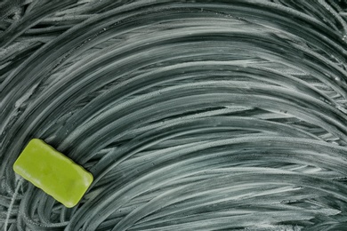 Dirty chalkboard with duster, closeup. School equipment