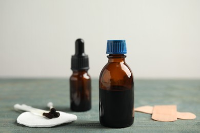 Bottles of medical iodine, cotton buds and sticking plasters on light blue wooden table, space for text