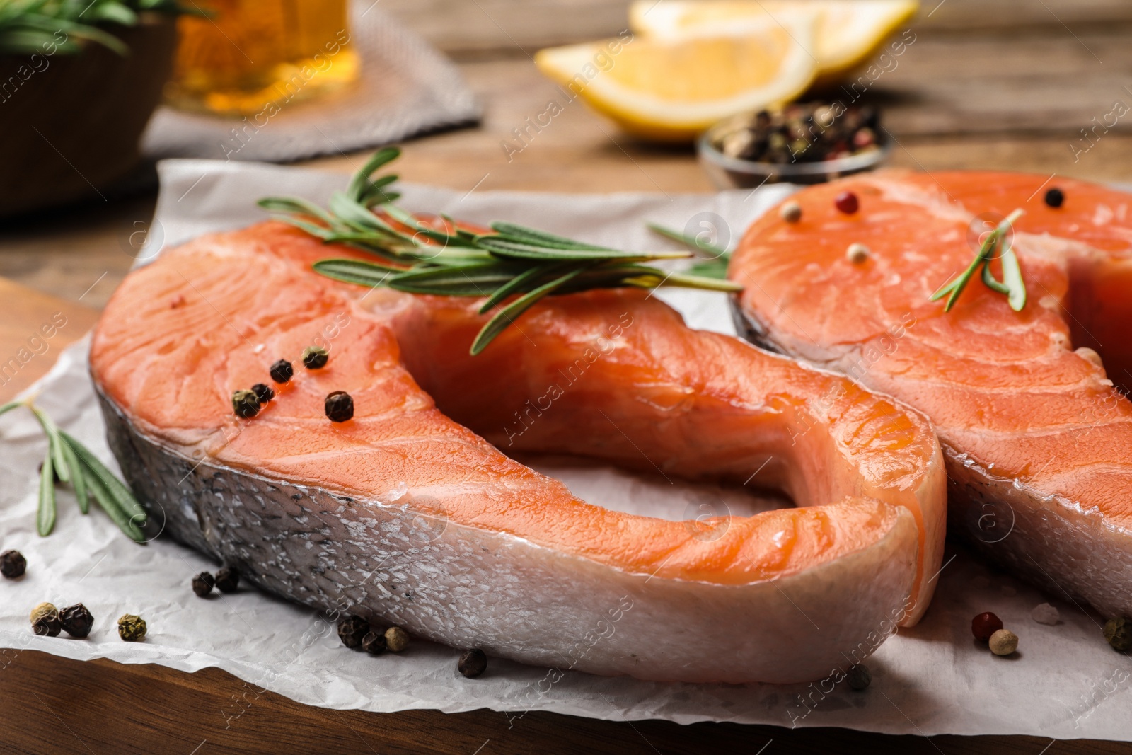 Photo of Fresh salmon steaks with spices and rosemary on table, closeup view