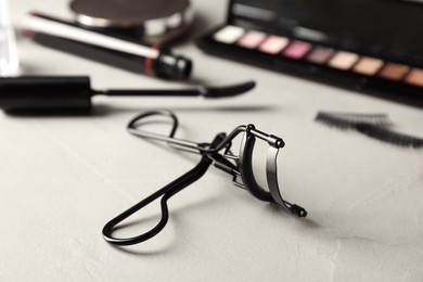 Photo of Eyelash curler on grey table, closeup. Makeup tool