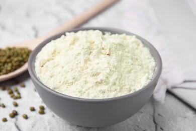 Photo of Mung bean flour in bowl and seeds on white textured table