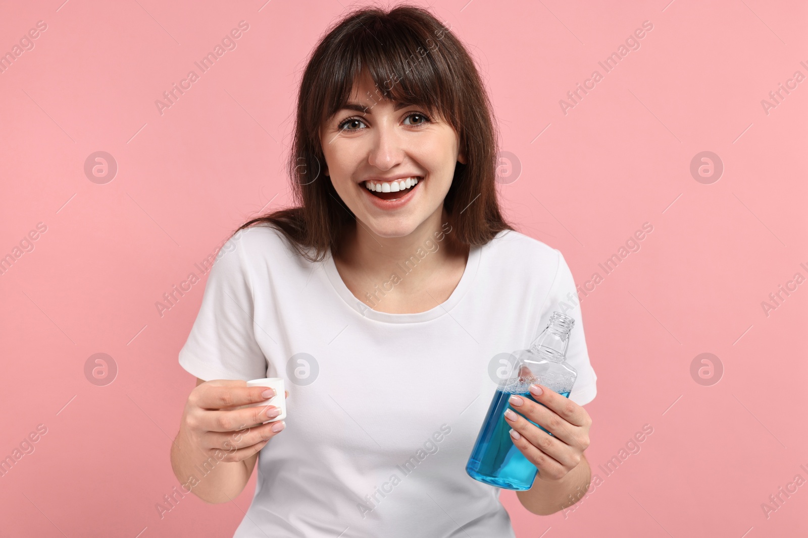 Photo of Young woman with mouthwash on pink background