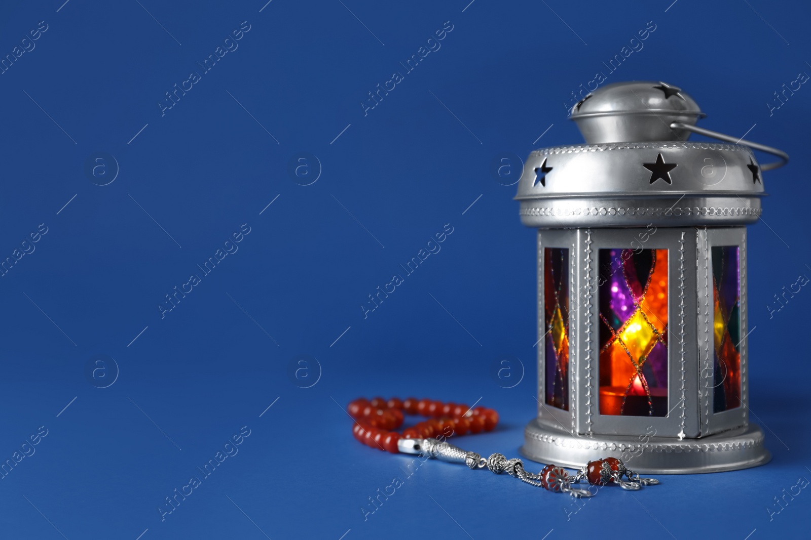 Photo of Decorative Arabic lantern and misbaha on blue background. Space for text