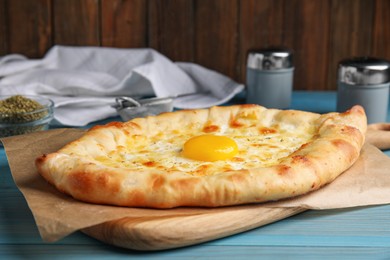 Fresh homemade khachapuri with cheese and egg on light blue wooden table