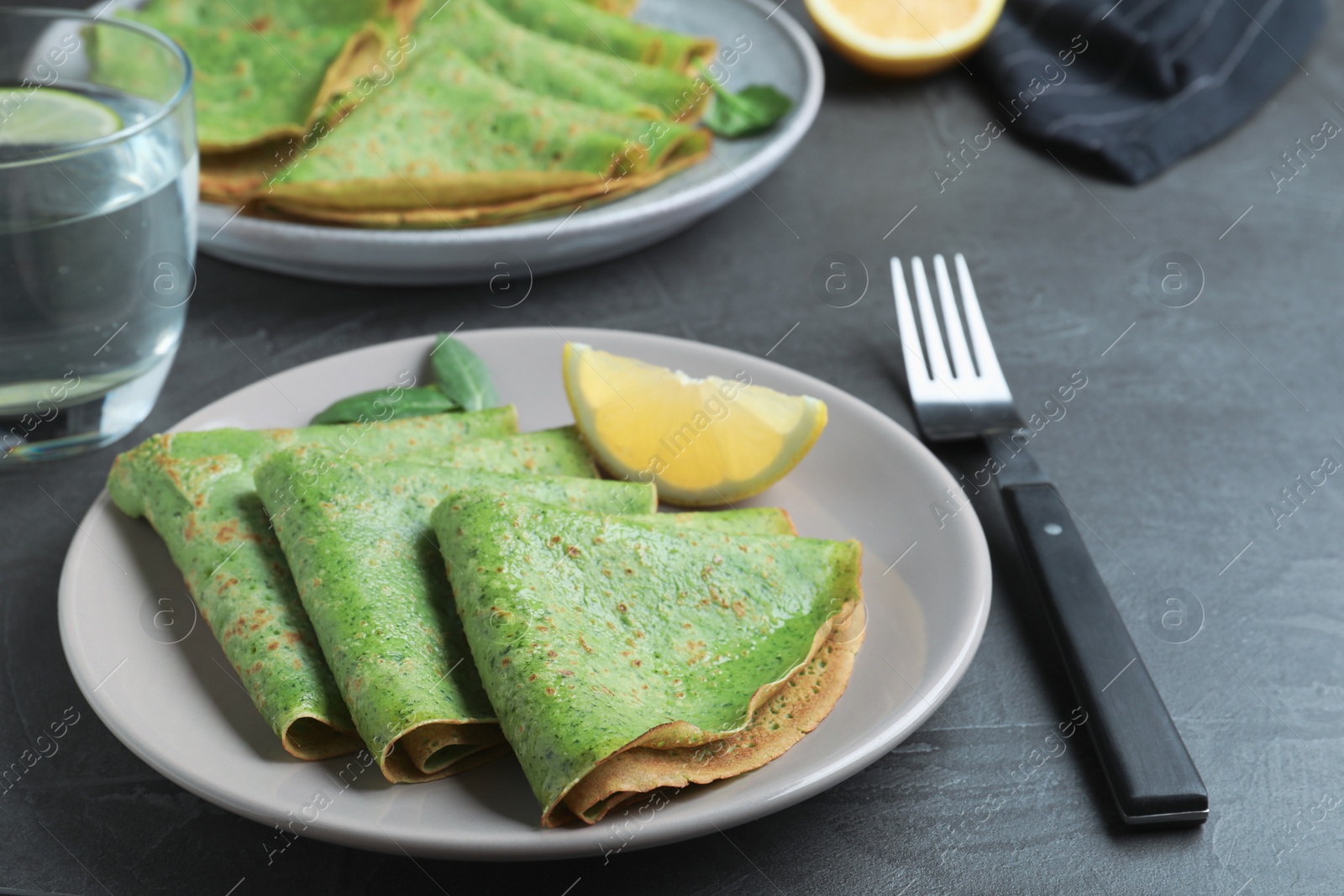 Photo of Tasty spinach crepes served on grey table, closeup