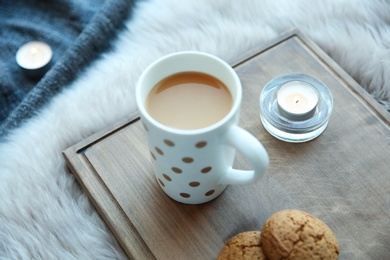 Burning candles, cup of coffee and cookies on wooden board