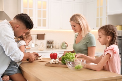 Photo of Happy family cooking together at table in modern kitchen