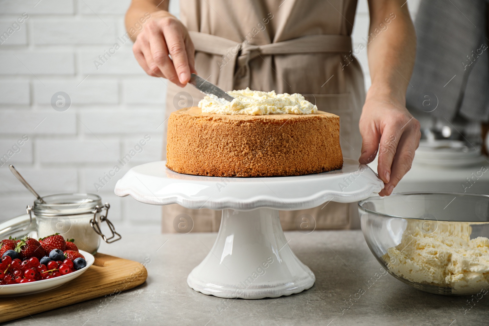 Photo of Woman decorating delicious cake with fresh cream at table indoors, closeup. Homemade pastry