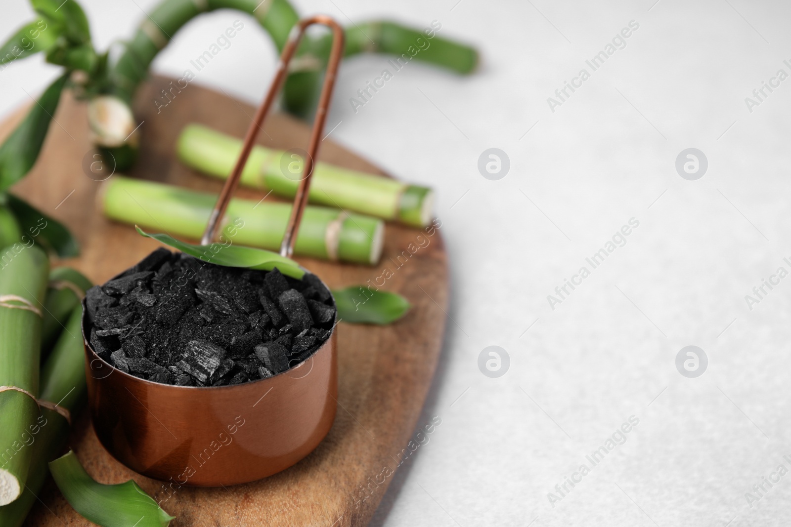 Photo of Fresh bamboo and charcoal on light gray table, closeup. Space for text