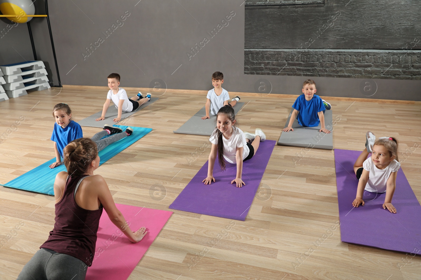 Photo of Cute little children and trainer doing physical exercise in school gym. Healthy lifestyle