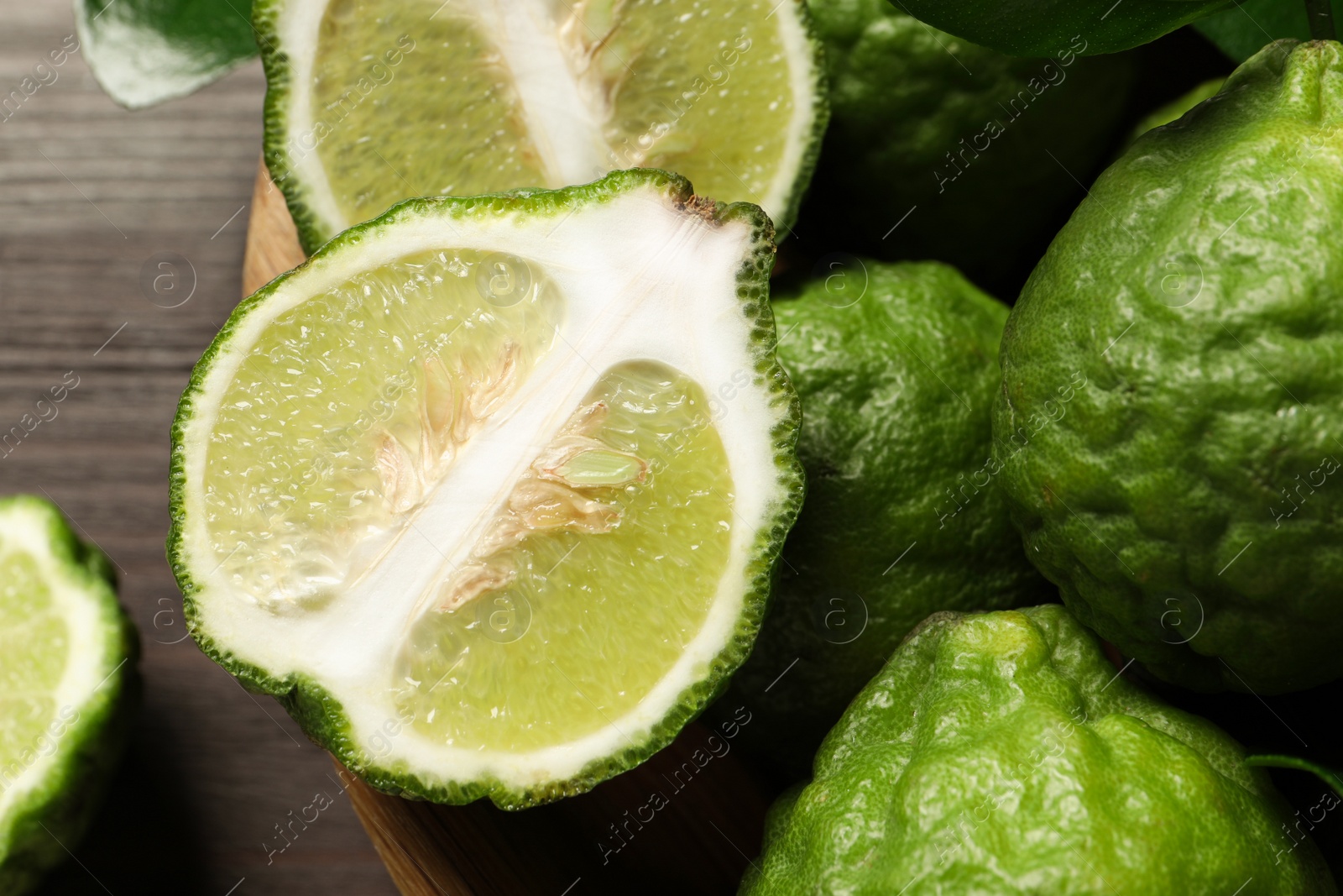 Photo of Whole and cut ripe bergamot fruits in bowl on table, closeup