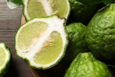 Photo of Whole and cut ripe bergamot fruits in bowl on table, closeup