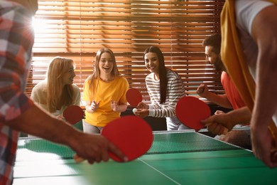 Happy friends playing ping pong together indoors