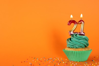 Photo of Delicious cupcake with number shaped candles on orange background, space for text. Coming of age party - 21th birthday