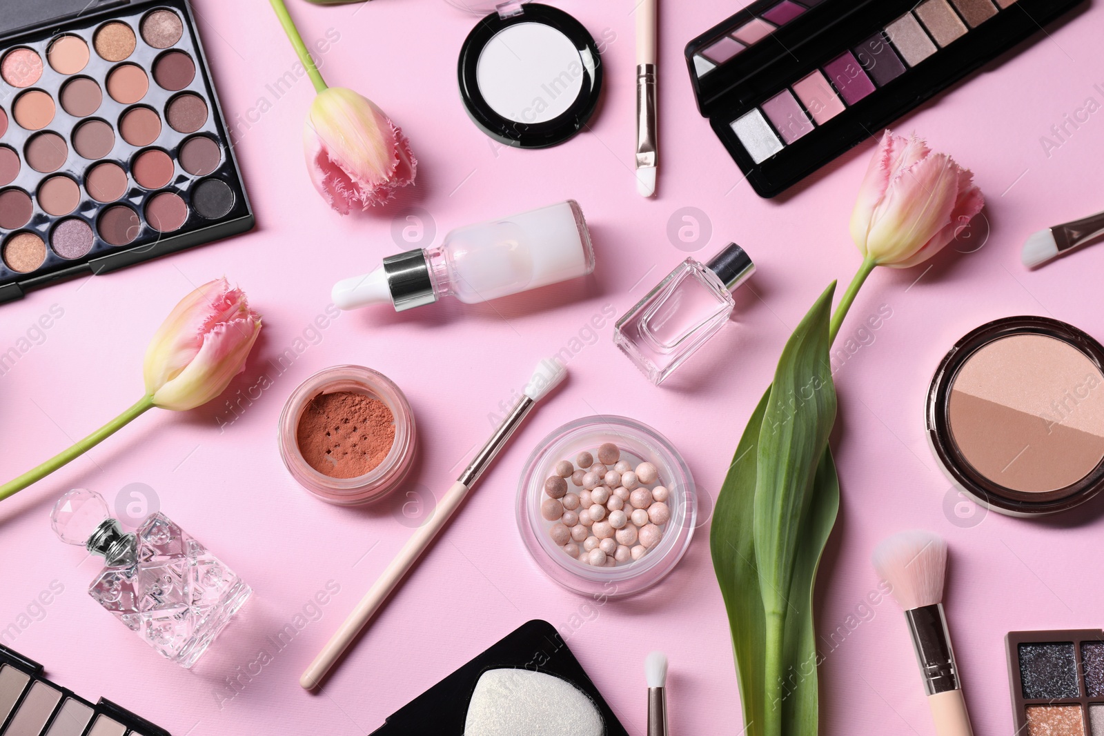 Photo of Flat lay composition with different makeup products and beautiful spring flowers on pink background